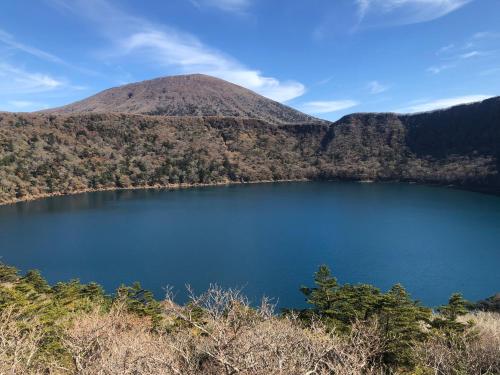 a mountain with a blue lake in the foreground at 貸別荘モザンピーク 完全貸切ログハウス in Kirishima