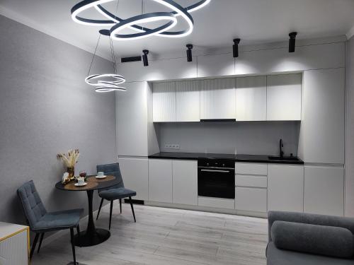 a kitchen with white cabinets and a table and a chandelier at 2-х комнатная квартира in Kokshetau
