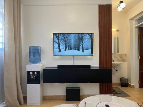 a living room with a tv on a wall at Tranquil Luxury Stay, Utawala, JKIA View in Nairobi