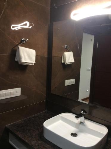 a bathroom with a sink and a mirror at Hotel The Saffron Park in Panchkula