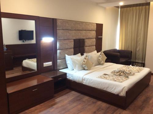 a hotel room with a bed and a mirror at Hotel The Saffron Park in Panchkula