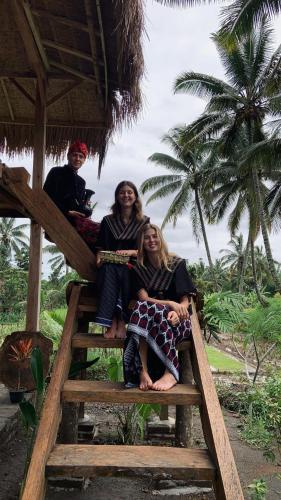 a group of three people sitting on a wooden stairs at Padi Bungalow in Tetebatu