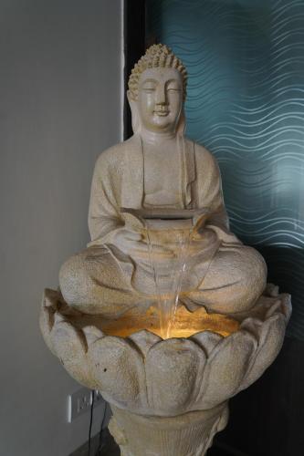 a statue of a buddha sitting in a fountain at Hotel The Saffron Park in Panchkula