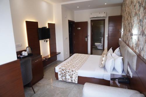 a hotel room with a bed and a television at Hotel The Saffron Park in Panchkula