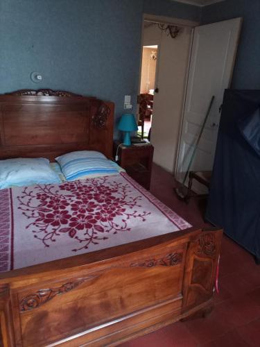 - une chambre avec un grand lit en bois et un couvre-lit rouge dans l'établissement Chambre individuelle, à Béziers