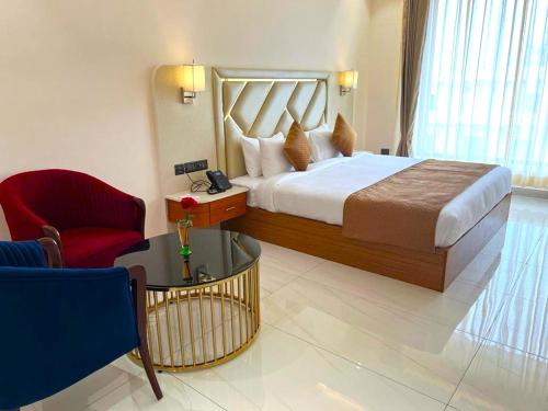 a hotel room with a bed and a red chair at The Velvista Hotel in Muzaffarnagar