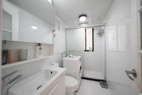 a white bathroom with a toilet and a sink at Tonight Homestay West Nanjing Road Branch Shanghai in Shanghai