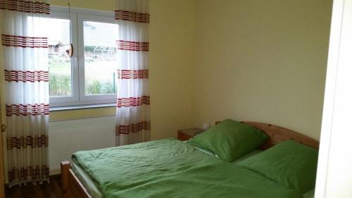 a bedroom with a bed and a window with curtains at Haus Seeblick in Alt Schwerin