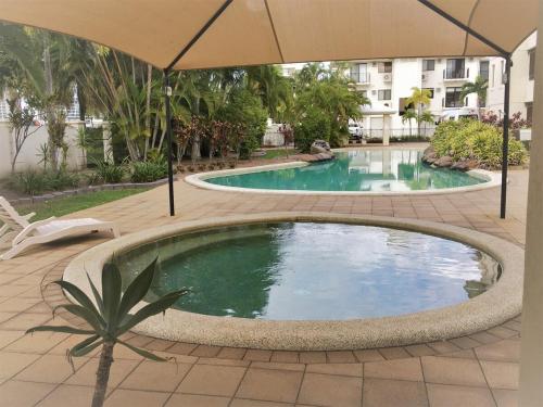 a large swimming pool with an umbrella in a courtyard at Strand Marina-Ground Floor with Courtyard in Townsville