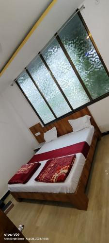 a bedroom with a bed with two large windows at Hotel Maharana Palace in Maheshwar