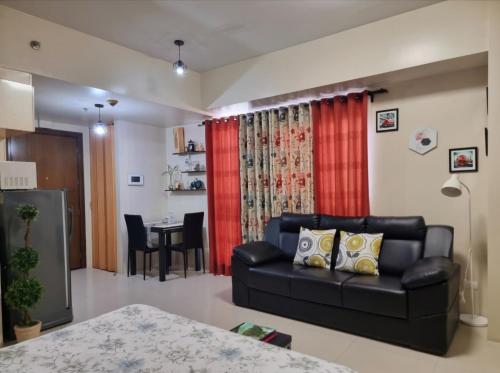 a living room with a black leather couch and a table at Condo Airport NAIA Terminal-3 One Palm Tree Villas in Manila