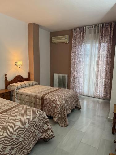 a hotel room with two beds and curtains at Hotel Mirasol in Órgiva