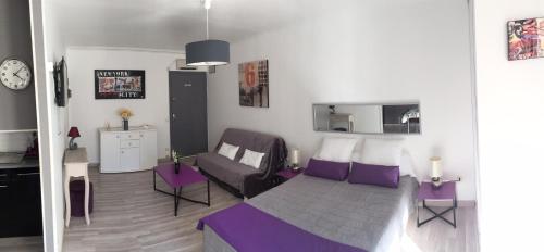 une chambre avec un lit violet et un canapé dans l'établissement Locations appartements standing Amélie-les-bains, à Amélie-les-Bains-Palalda