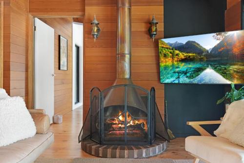 a fireplace in a living room with a tv on the wall at Hil & Jack's Riverfront Cabin, Merrijig Mt Buller in Merrijig
