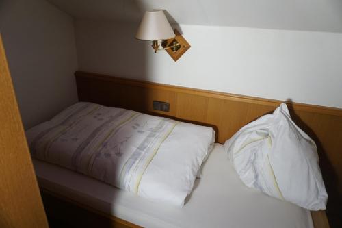 a bed with two pillows and a lamp on the wall at Gasthof Torwirt in Sankt Lambrecht