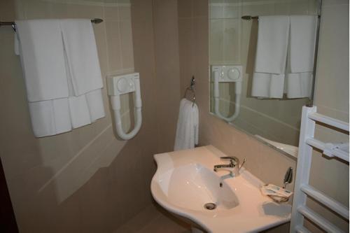 a bathroom with a sink and a mirror and towels at Dafovska Hotel in Pamporovo
