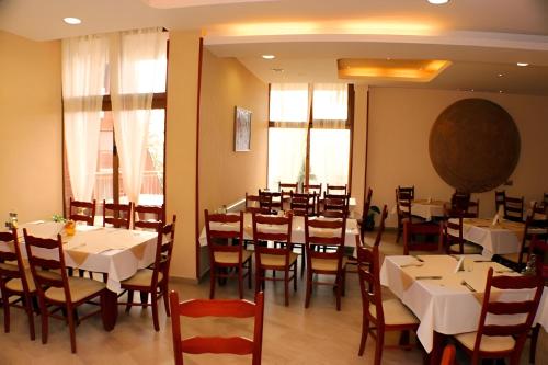 a dining room with white tables and chairs at Dafovska Hotel in Pamporovo
