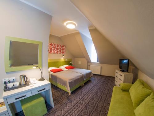 sypialnia z łóżkiem, telewizorem i kanapą w obiekcie Hotel *** NAT Krynica Zdrój w mieście Krynica Zdrój