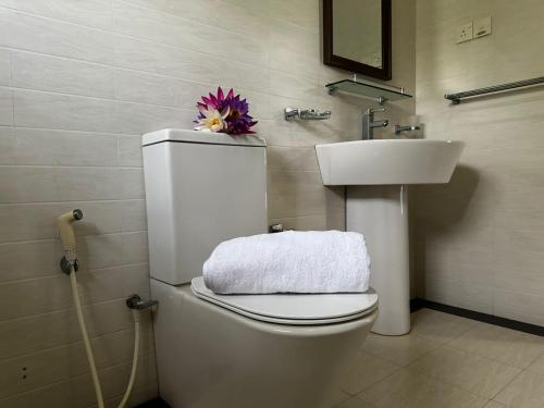 a bathroom with a white toilet and a sink at Curve Hiri in Dickwella