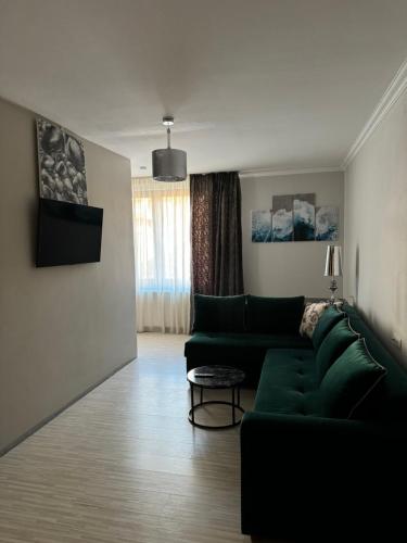 a living room with a green couch and a table at Pensiunea Sun Victor in Baile Felix