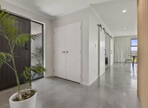 a hallway with white doors and a potted plant at Modern and Spacious 4 bedroom Home only 2yo in New Plymouth