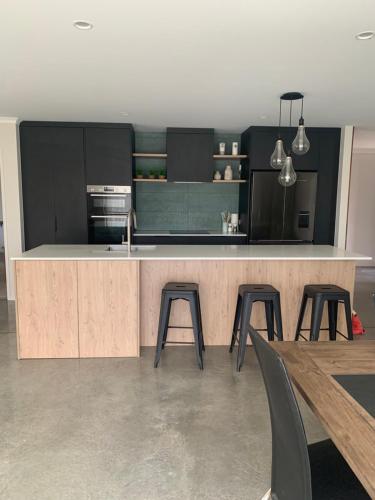 a kitchen with a counter and some chairs and a table at Modern and Spacious 4 bedroom Home only 2yo in New Plymouth