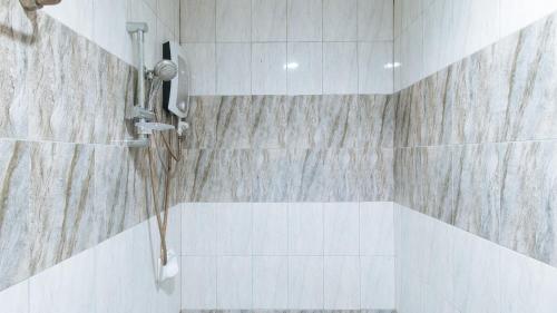 a bathroom with a shower with white tiles at WestCourt Inn Ilocos Sur in Bantaoay