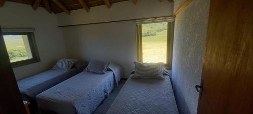 two beds in a room with two windows at Casa de campo, La Resolana in Rivera