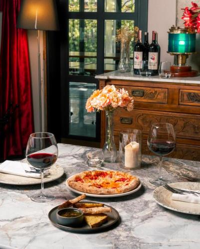 a table with a pizza and two glasses of wine at Urla Köstem Müze Otel in Uzunkuyu