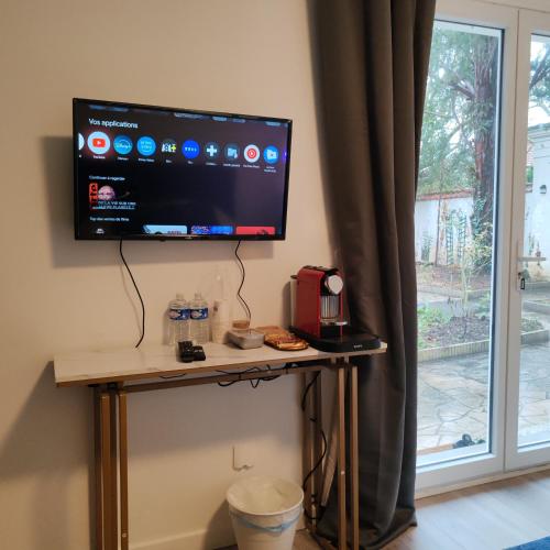 a flat screen tv on a table next to a window at Le patio Aristide in Champigny-sur-Marne