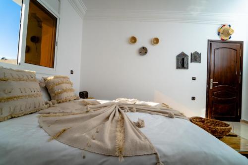 a white bedroom with a large bed with a blanket at Ossmon Surf House - Anza in Agadir