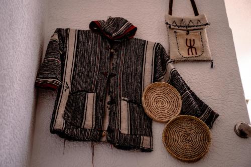 a blanket hanging on a wall with hats and a clock at Ossmon Surf House - Anza in Agadir