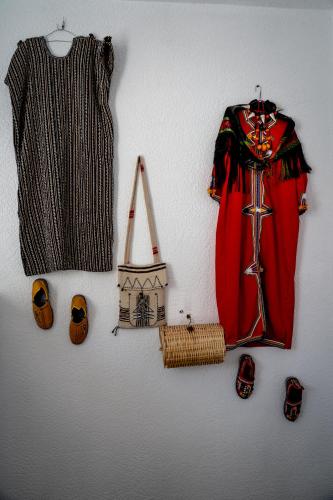 a wall with a dress and other clothes and shoes at Ossmon Surf House - Anza in Agadir