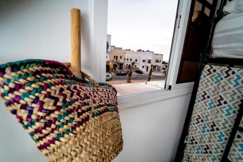 a basket on a window sill with a view of a street at Ossmon Surf House - Anza in Agadir
