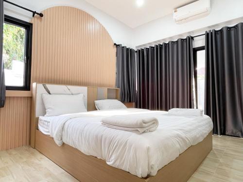 a bedroom with a large bed with white sheets at 4BR Home with large beds near mall & beaches in Ban Tha Rua