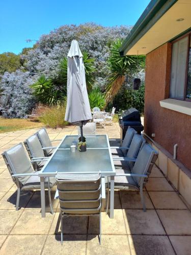 a table with chairs and an umbrella on a patio at BayView in Port Elliot