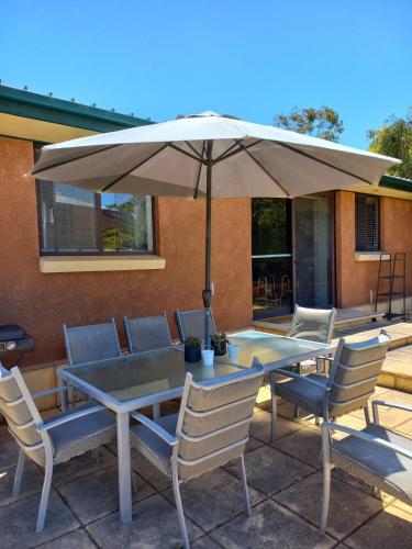 a table and chairs with an umbrella on a patio at BayView in Port Elliot