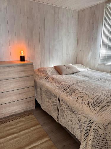 a bedroom with a bed and a dresser with a lamp at Yttervik gard in Steinkjer