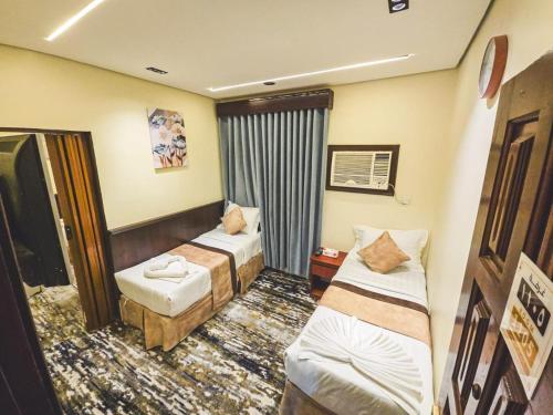 a hotel room with two beds and a chair at Jawad Al-Taj Hotel in Mecca