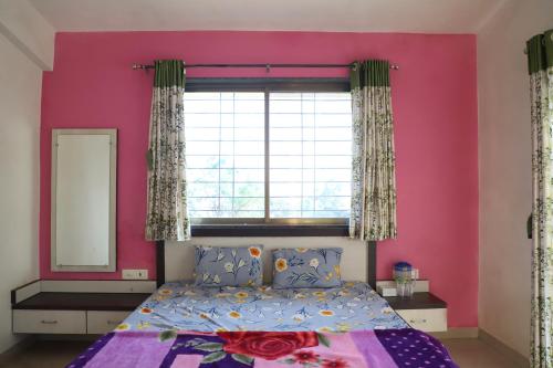 a pink bedroom with a bed and a window at ShriHari Villa in Panchgani