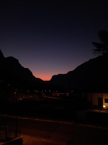 a sunset in the mountains with a palm tree at Casa del piccolo olivo in Strigno