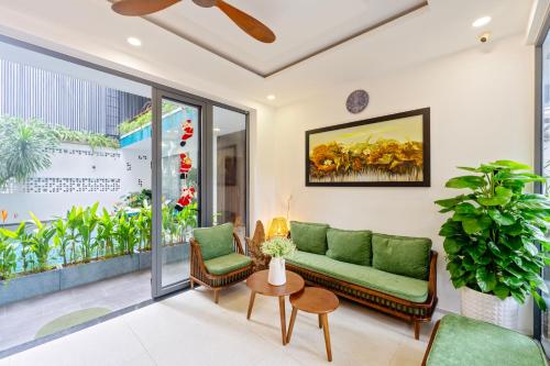 a living room with a green couch and a table at The Nam An Villa Hoi An in Hoi An