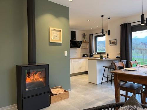 een woonkamer met een open haard naast een keuken bij Les midis au vert - La Bâtisse - 4 personnes in Stavelot