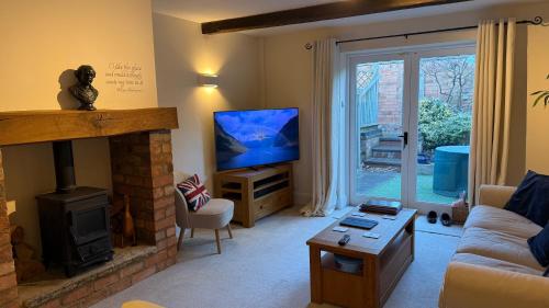 a living room with a fireplace and a television at The Old Coach House in Stratford-upon-Avon