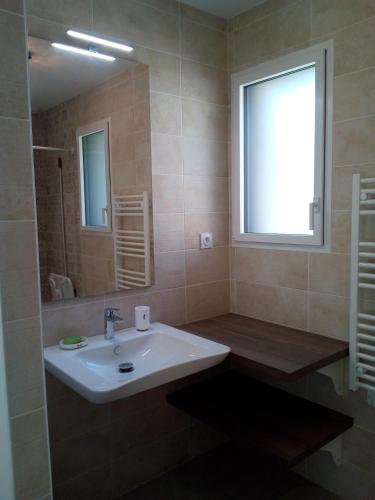 La salle de bains est pourvue d'un lavabo, d'une fenêtre et d'un miroir. dans l'établissement Gîte pOm de Reinette, aux Herbiers