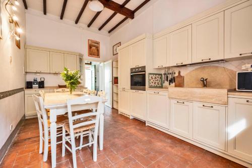a kitchen with white cabinets and a table and chairs at Tenuta di Megognano in Poggibonsi