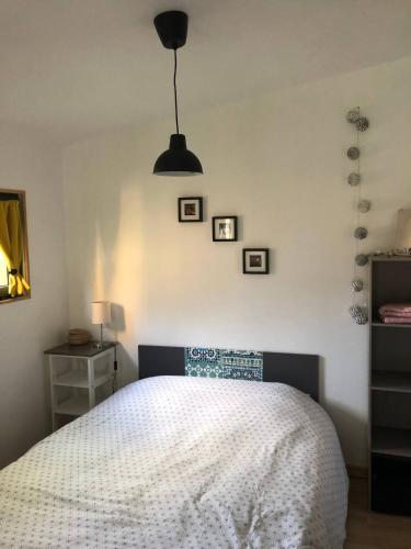 - une chambre avec un lit blanc et une lampe noire dans l'établissement Le Petit Chalet de la Plage - Terrasse & Jardinet, à Portbail