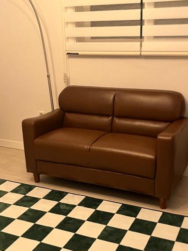 a brown leather couch in a room with a checkered floor at Gangnam Rooftop Glamping in Seoul