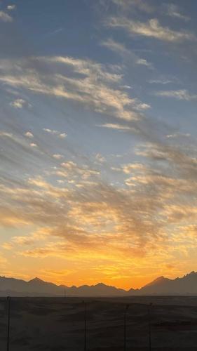 a sunset in the desert with a fence and mountains at Sky Star Hotel free shuttle to Hurghada City center in Hurghada