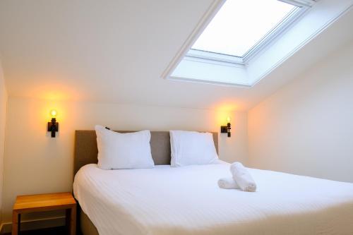 a bedroom with a white bed with a skylight at Herberg de Boelekeerl in Halle